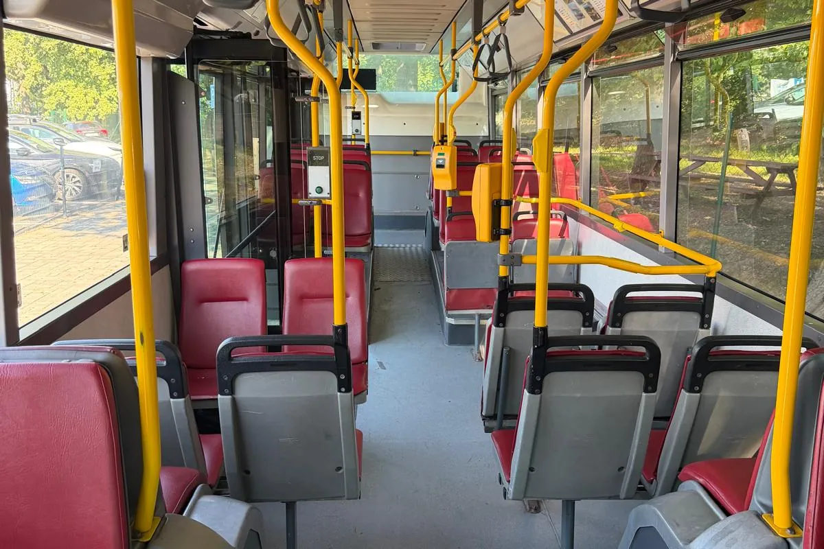 Interiér autobusu Karosa City Bus s červenými sedačkami a žlutými madly