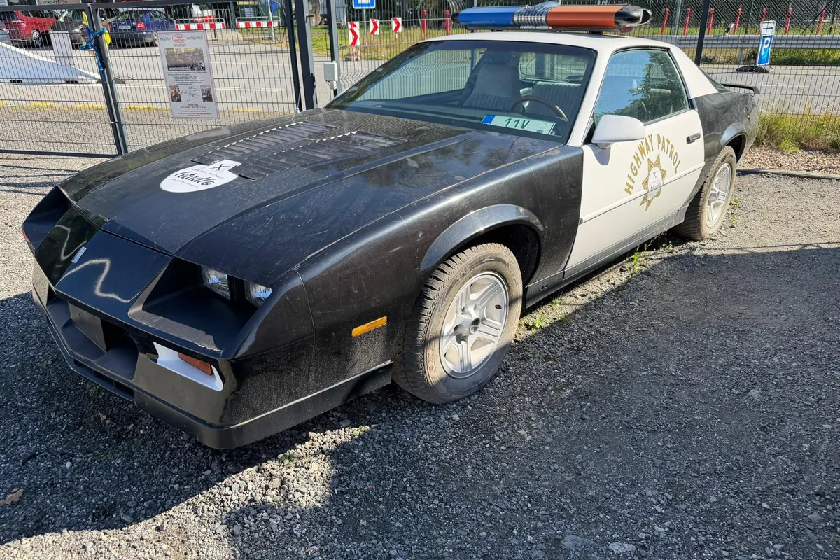 Černobílý Chevrolet Camaro v barvách Highway Patrol s rampou majáků na střeše