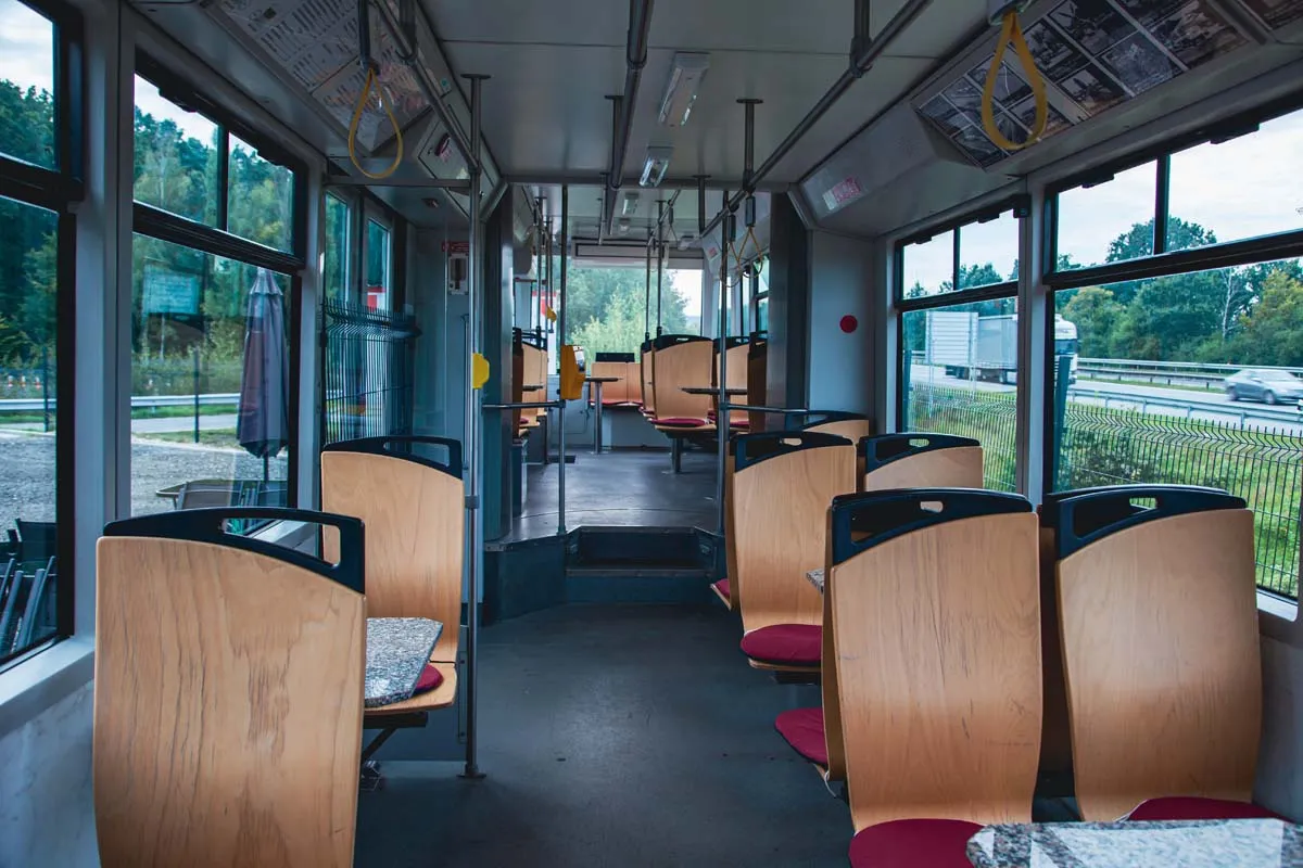 Interiér tramvaje Škoda Astra s původními sedačkami a stolky, výhled na dálnici D10