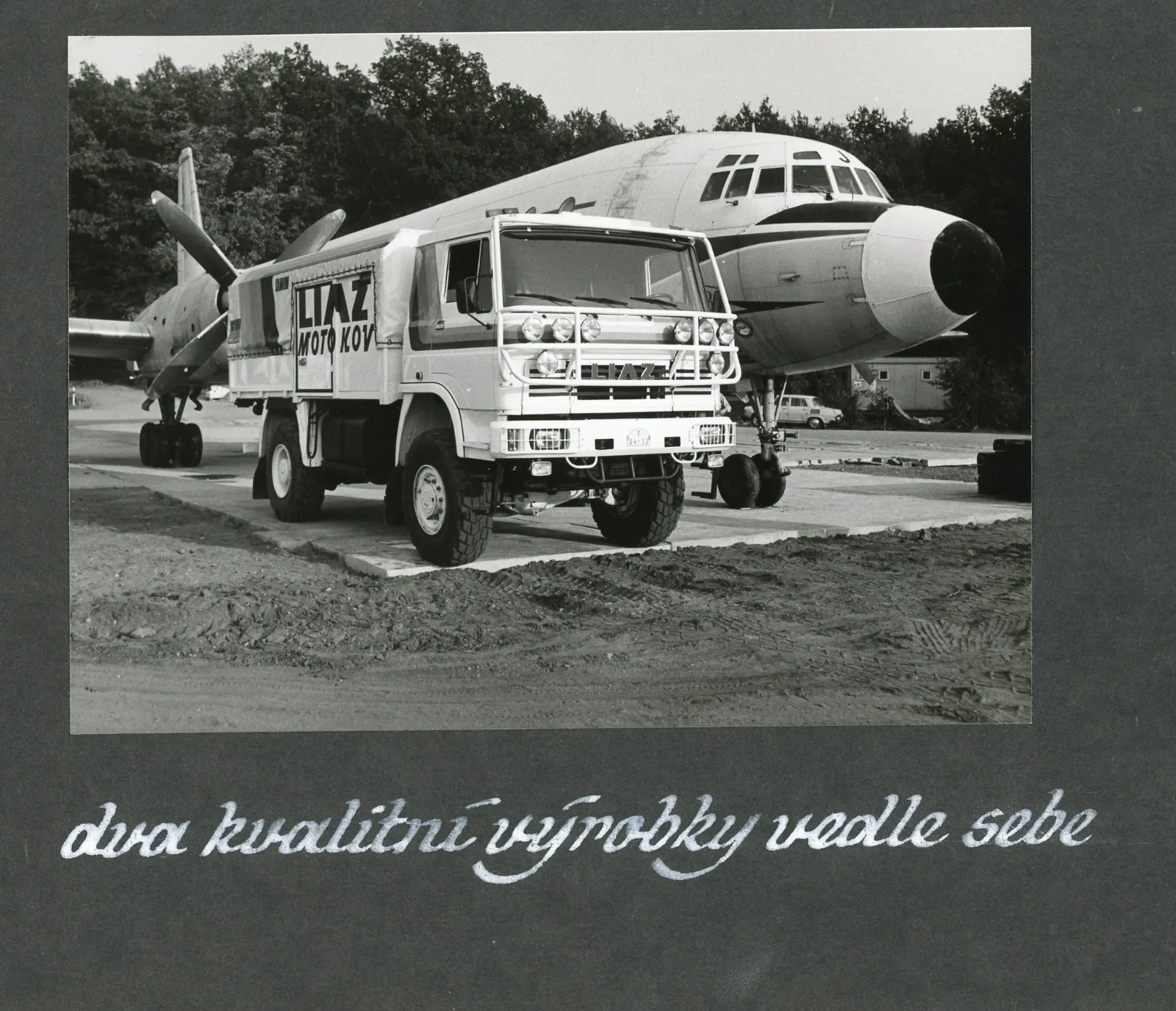 Historická fotografie — závodní LIAZ a letoun Il-18 s popiskem „dva kvalitní výrobky vedle sebe“
